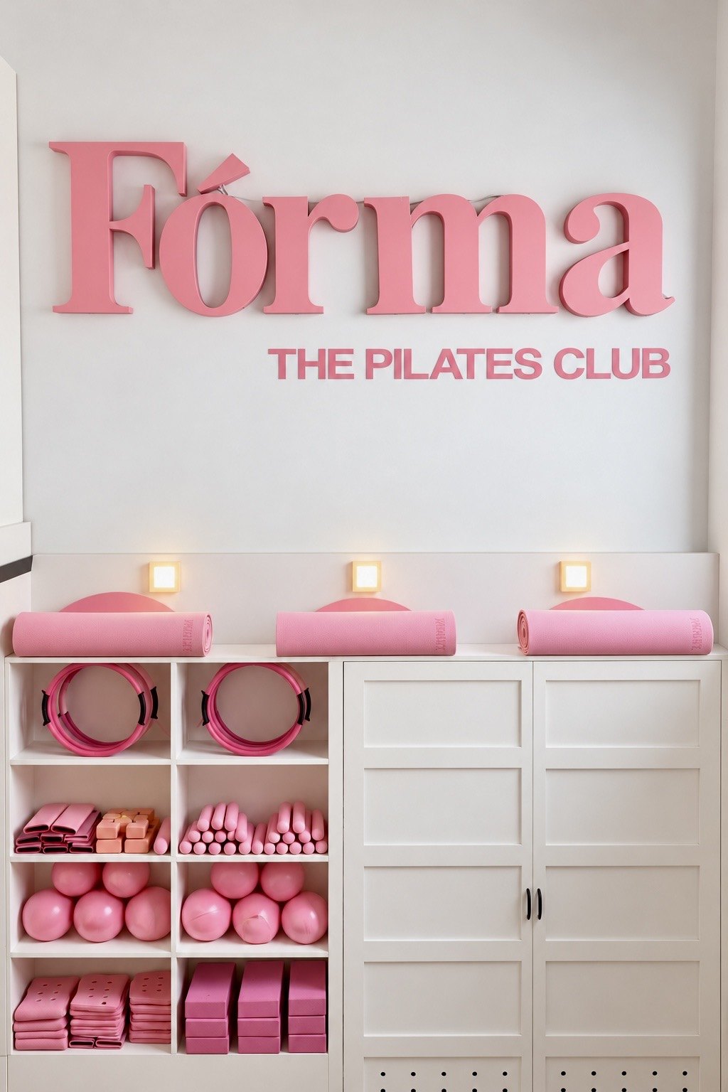 The pink Fórma, The Pilates Club sign above the studio shelves of pink mats, rings and balls